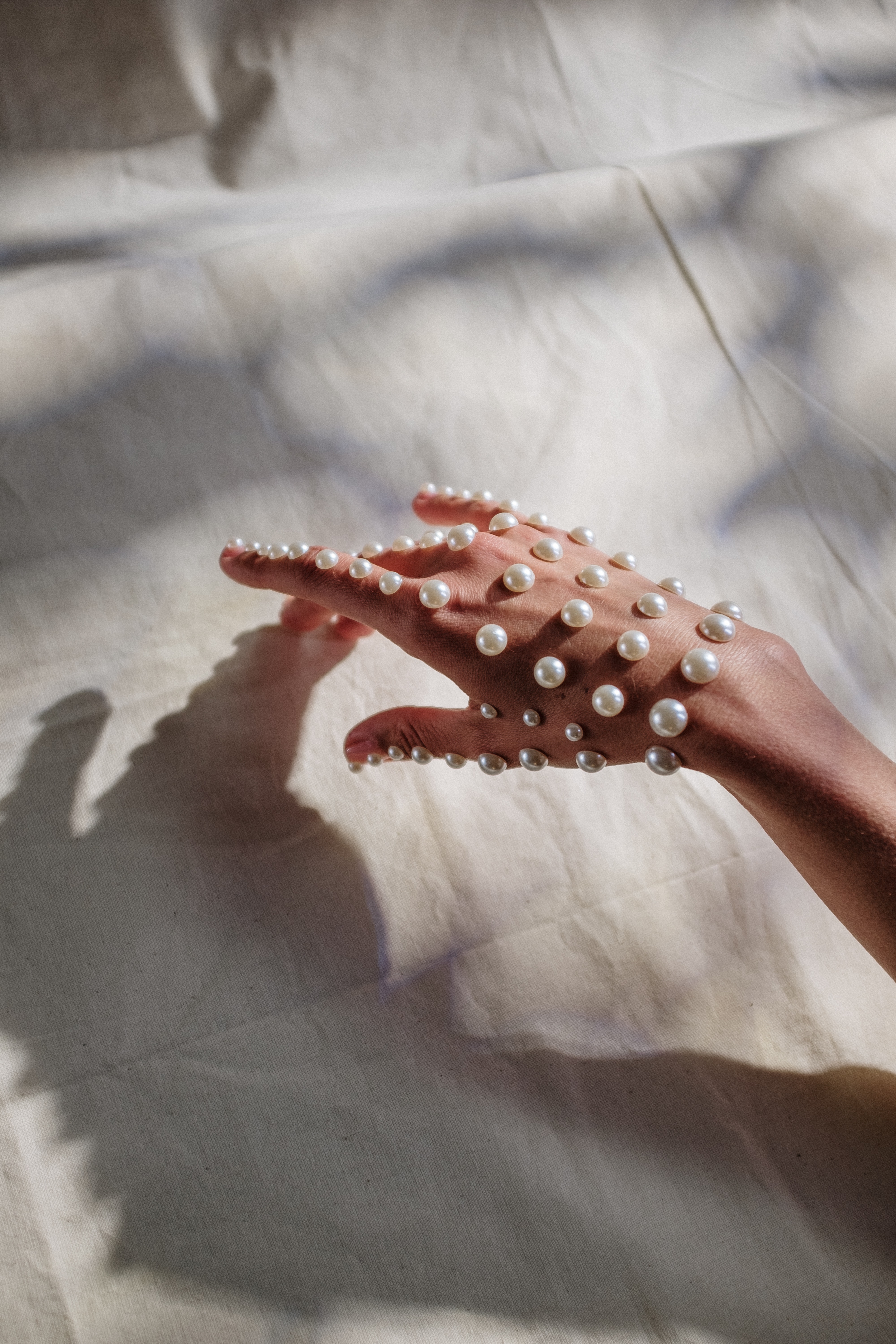 Pearls on hand touching white fabric